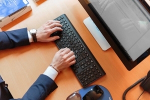 Bild von Mann mit Anzug schreibend an der Tastatur eines Computers