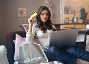 Bild von junger Frau mit Kreditkarte in der Hand, vor dem Laptop sitzend